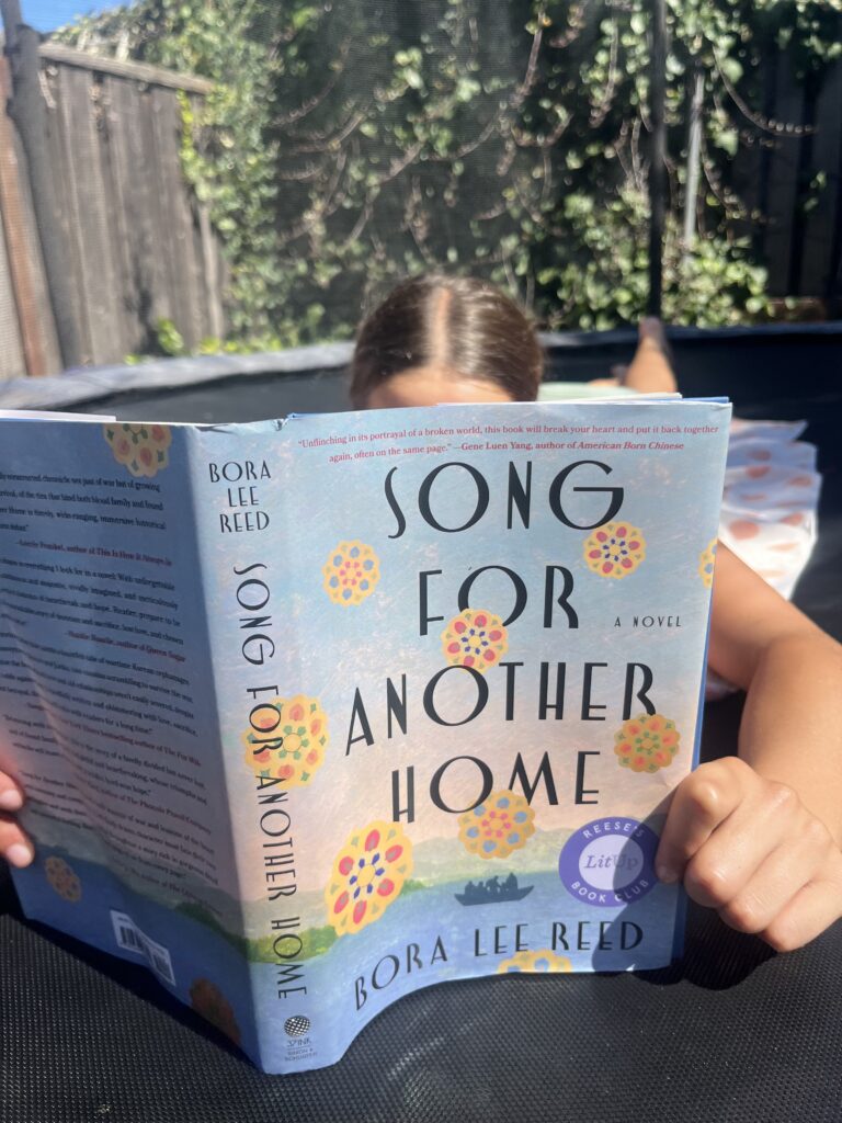A reader holding Song for Another Home